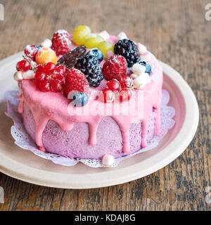 Süße Käsekuchen mit frischen Beeren und Joghurt Creme. Lecker Himbeeren Kuchen mit frischen Erdbeeren, Himbeeren, Heidelbeeren, Johannisbeeren und Blackberry Früchte auf rustikalen Holzmöbeln Hintergrund. Stockfoto