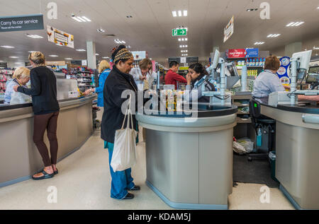 Kunden stehen an den Kassen an der Peterborough Zweig der Supermarkt Waitrose, Cambridgeshire, England, UK. Stockfoto