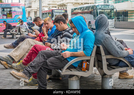 Junge Männer Bauarbeiter, Tragen von Arbeitskleidung, eine Pause machen und draußen auf einer Bank sitzen, in South Kensington, London, England, UK. Stockfoto