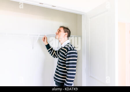 Junger Mann Kontrolle in kleinen Schrank in neue Zimmer nach oder vor dem Einzug, während Open House suchen Stockfoto