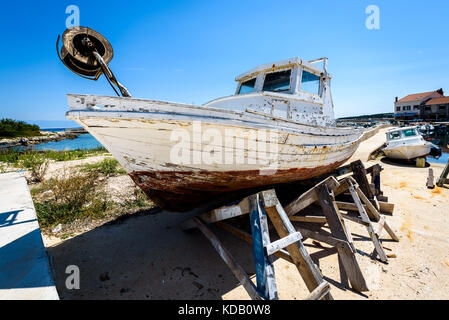 Reparatur und Restauration von alten hölzernen Angeln Schiff oder Boot. alte verwitterte Fischerboot montiert auf Holz- Buchsen für Dry Dock Renovierung und Reparatur mit Stockfoto