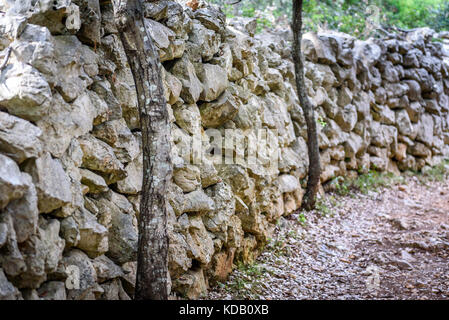 Stein rock Zaun oder gabione, Straße und Bürgersteig. alt Felswand Struktur und einen Weg in der Wüste. Stockfoto