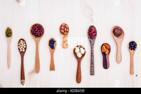 Auswahl an Bohnen und Linsen in Löffel aus Holz auf Holz- Hintergrund. Mung Bohnen, Soja, rote Kidney-bohnen, Schwarze Bohne, rote Bohne, Mandeln, Pista Stockfoto