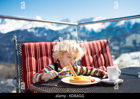 Müde, schläfrig Kind im Restaurant in den Bergen. Familie in apres ski Mittagessen in Alpine Resort. Kinder essen nach dem Skifahren. winter schnee Spaß für Stockfoto