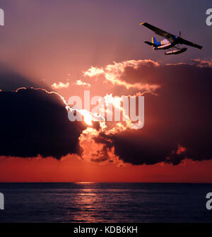 Wasserflugzeug hoch über dem Meer bei Sonnenuntergang Stockfoto