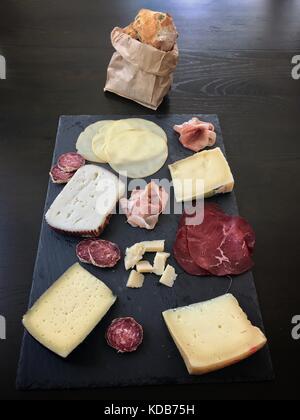 Italienische Antipasti Snacks: Parmaschinken, Salami, Käse Vielfalt auf schiefer Fach mit Brot auf dunklen Holztisch serviert. top View Stockfoto