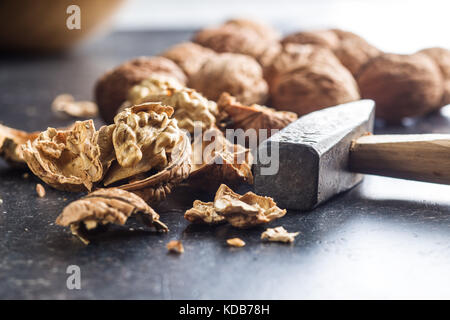 Leckere getrocknete Walnüsse und Hammer auf alten Küchentisch. Stockfoto