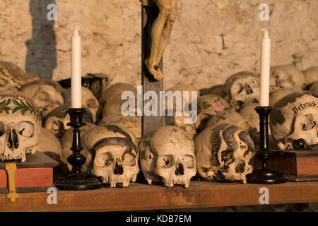 Bemalte Schädel mit Namen, Kerzen und Kreuz (Hallstatt, Österreich) Stockfoto