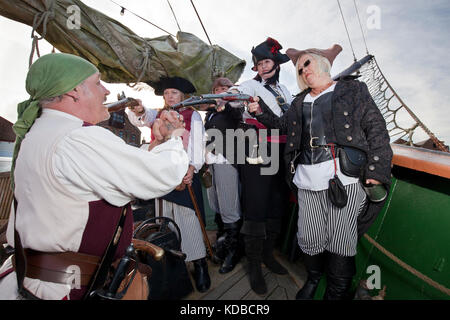 Weiblichen Piraten halten die männlichen Schiff Kapitän mit Waffengewalt während Brunnen Pirate Festival auf und rund um das 19. Jahrhundert schooner Albatros. Stockfoto