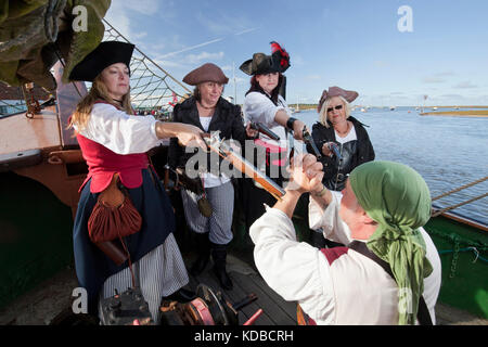 Weiblichen Piraten halten die männlichen Schiff Kapitän mit Waffengewalt während Brunnen Pirate Festival auf und rund um das 19. Jahrhundert schooner Albatros. Stockfoto