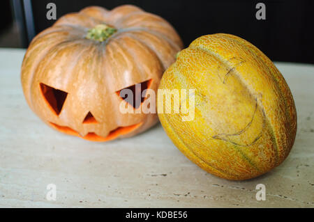 Zwei Jack-o'-Laternen aus Kürbis und Melone am Küchentisch im Prozess der Herstellung. Konzept halloween Hintergrund Stockfoto