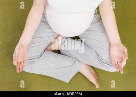 Blick von oben auf die schwangere Frau in Lotus Position Stockfoto
