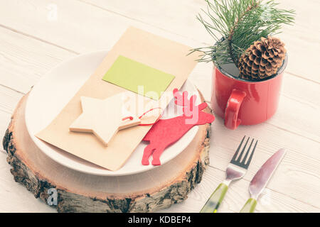 In der Nähe von Weihnachten Abendessen Festlegung. Platte auf Holzbrett mit Menü Karte mit Weihnachtsdekor Stockfoto