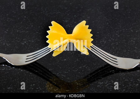 Gelbe Farfalle Pasta auf 2 Gabeln vor dunklem Hintergrund. Stockfoto