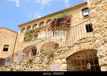 Schönes Steinhaus mit Blumen an der Wand in der mittelalterlichen Stadt Pals, in der Mitte des Emporda Region Girona, Katalonien, spai Stockfoto