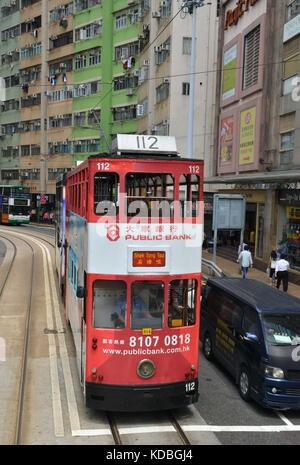 An der Unterseite der Gebäude, bunte doppelstöckigen Straßenbahn vom Hong Kong Straßenbahnen mit großen Werbung auf seinen Seiten. Öffentliche Bank Anzeige *** Lokale Stockfoto