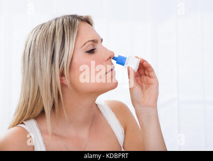 Nahaufnahme einer Frau mit Nasenspray auf weißem Hintergrund Stockfoto