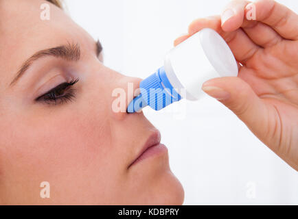 Nahaufnahme einer Frau mit Nasenspray auf weißem Hintergrund Stockfoto