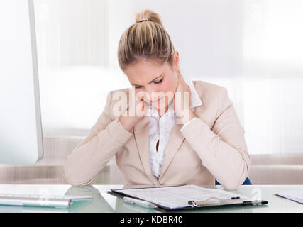 Junge Geschäftsfrau leiden unter Nackenschmerzen im Büro Stockfoto