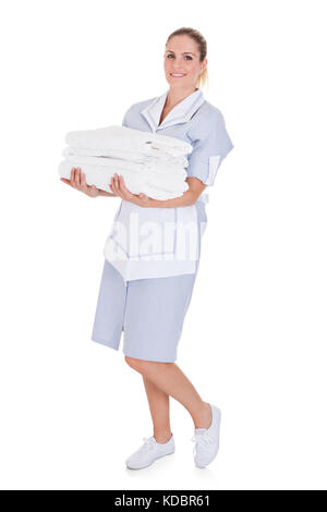 Glückliche junge Maid holding Handtücher über weißen Hintergrund Stockfoto