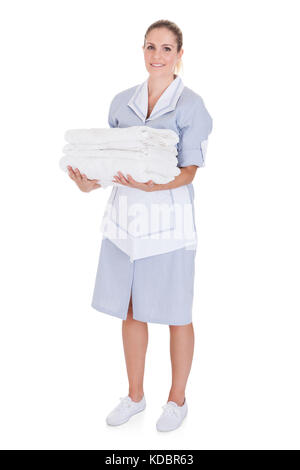 Glückliche junge Maid holding Handtücher über weißen Hintergrund Stockfoto