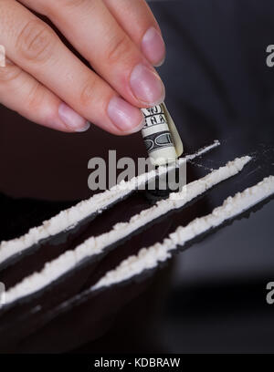 Nahaufnahme einer Person Schnupfen von Kokain Drogen mit gerollten Geldschein Stockfoto