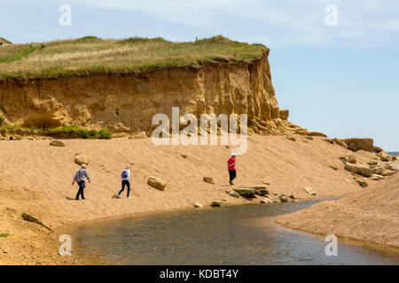 Eine Gruppe der Wanderer entlang des Flusses Braut, wo es das Meer trifft auf Burton Süßwasser auf der Jurassic Coast, Dorset, England, Großbritannien Stockfoto