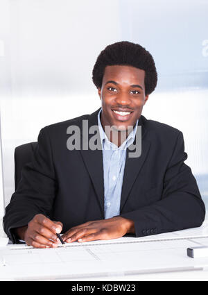 Porträt des glücklichen Architekten mit Blaupause im Büro Stockfoto