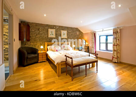 Große, luxuriöse Schlafzimmer mit unverputzten Steinwänden und en suite Stockfoto