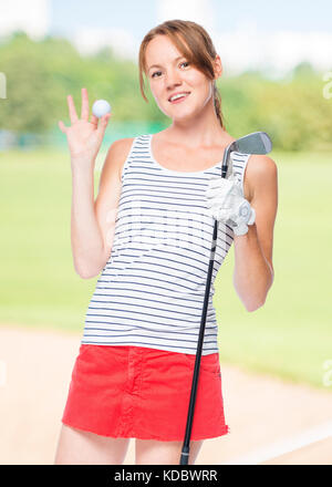 Mädchen erfolgreicher Golfspieler mit Requisiten für das Spielen auf einem Hintergrund der Golfkurse posing Stockfoto