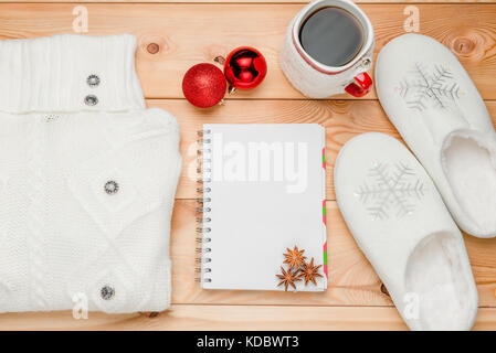 Ein warmer Pullover, Hausschuhe und ein Notebook für das Schreiben Wünsche im neuen Jahr Stockfoto