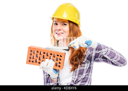 Frau Builder mit einem Ziegelstein in einem gelben Schutzhelm vor einem weißen Hintergrund Stockfoto