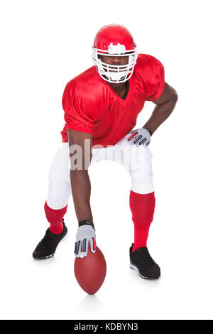 Portrait von American Football Spieler in der angreifenden Position auf weißem Hintergrund Stockfoto