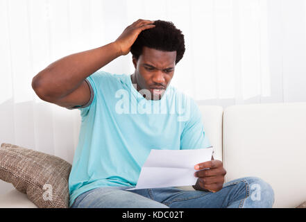Porträt von einem besorgten jungen afrikanischen Mann, einen Blick auf das Dokument Stockfoto