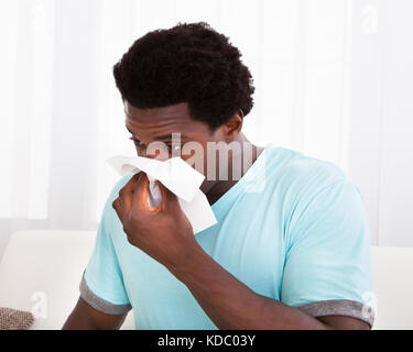 Afrikanische jungen Mann in einem kalten Holding Gewebe und seine Nase weht Stockfoto