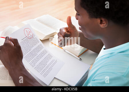 Glücklich afrikanische männlichen Studenten zeigt eine Papier mit perfekten Grade ein Plus im Klassenzimmer Stockfoto