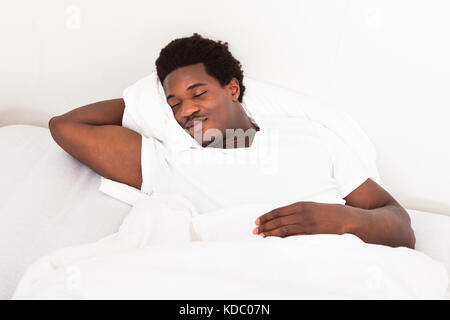 Hübscher junger afrikanischen Mann schlafend im Bett zu Hause Stockfoto