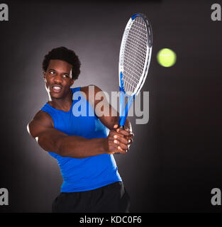 Junge Afrikaner Tennisspielen mit Tennisschläger Stockfoto