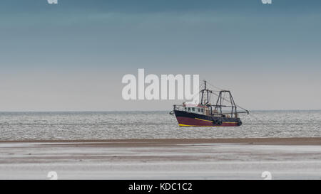 Eine kleine Fischtrawler direkt an der Küste an der Küste mit ihren Netzen in das Wasser fallen gelassen und sehr nahe an der Küste Stockfoto