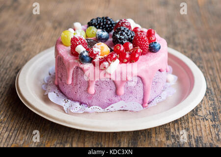 Süße Käsekuchen mit frischen Beeren und Joghurt Creme. Lecker Himbeeren Kuchen mit frischen Erdbeeren, Himbeeren, Heidelbeeren, Johannisbeeren und Blackberry Früchte auf rustikalen Holzmöbeln Hintergrund. Stockfoto