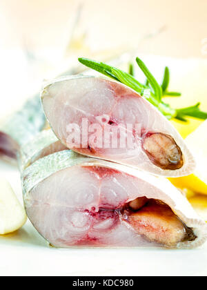 Frisch schneiden Makrele in Olivenöl mit Knoblauch und Rosmarin auf die weiße Platte. selektive Fokus flache Tiefenschärfe. Stockfoto
