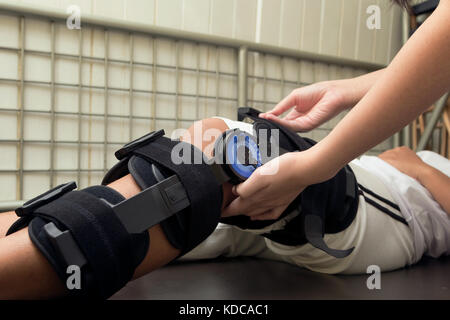 Weibliche Physiotherapie einstellen zu Fuß am Bein des Patienten in der Klinik Strebe Stockfoto