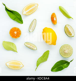 Gemischte frische Zitrusfrüchte und Blätter Hintergrund. frische Zitronen, Zitronenscheibe, Lime und orange auf weißem Holztisch mit Flach. Stockfoto