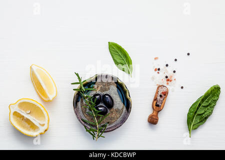 Basilikum Vinaigrette Dressing Zutaten auf weißem Hintergrund mit Holz flach frisches Basilikum Blätter, Zitrone, Olivenöl und schwarzen Oliven, ihn Stockfoto