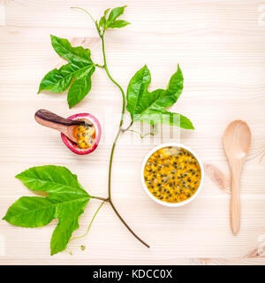 Frische Passionsfrüchte auf Holz- Hintergrund. saftige Passionsfrüchte mit grünen Blättern und Passionsfrucht Weinstock flach. Stockfoto