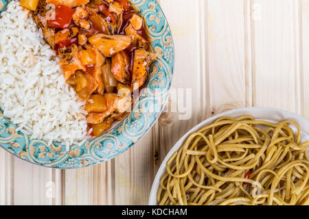 Kantonesischen Stil süß und sauer Huhn mit weissem Reis gegen einen hellen Hintergrund aus Kiefernholz Stockfoto