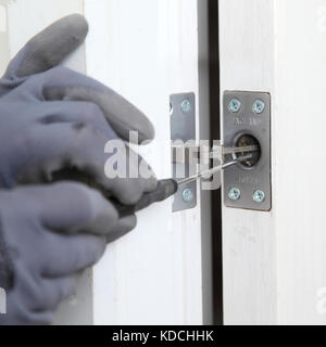 Ein Arbeiter installiert im Rahmen der Sanierung eines Wohnblocks in London, Großbritannien, eine verborgene näher an einer neuen Brandschutztür. Stockfoto