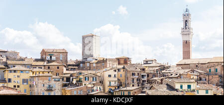 Horizontale Foto mit Blick auf den Rathausturm über die Häuser und Gebäude in der historischen Altstadt von Siena in Italien Toskana. der Himmel ist blau Stockfoto