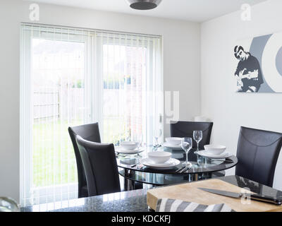 Ein rundes Glas Tisch mit Stühlen, für eine Mahlzeit in einem modernen Schwarzweiß gestaltete Wohnküche eines zeitgenössischen uk Home gekleidet. Stockfoto