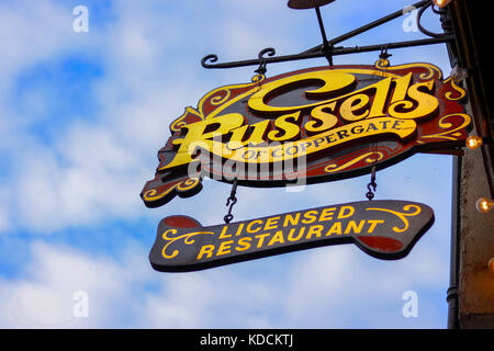 Russells der Coppergate Zeichen in der historischen Stadt York in Yorkshire, England Schuß gegen einen blauen und bewölkter Himmel Stockfoto